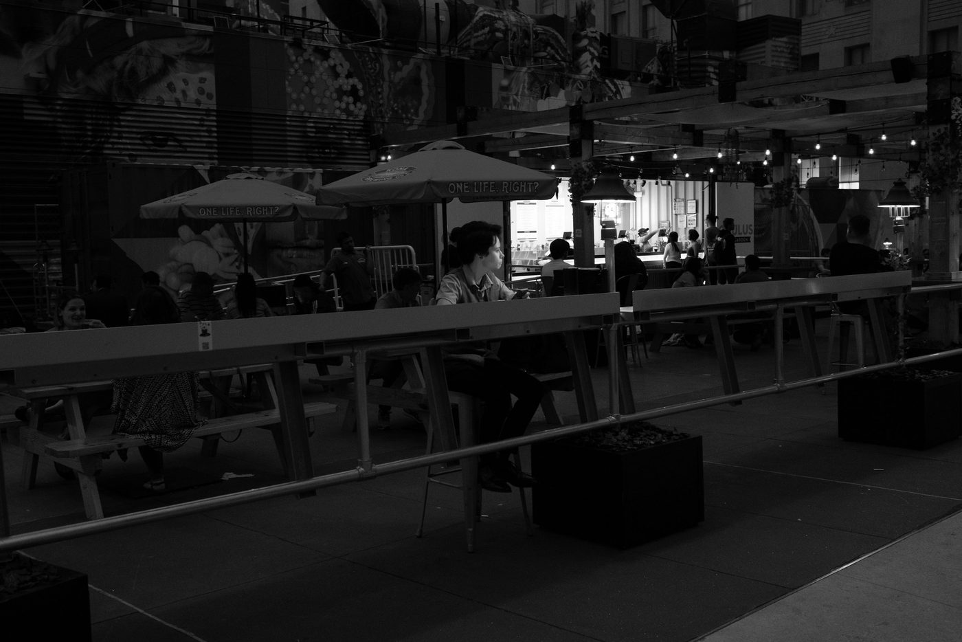 Lively terrace under parasols and string lights in the evening, New York