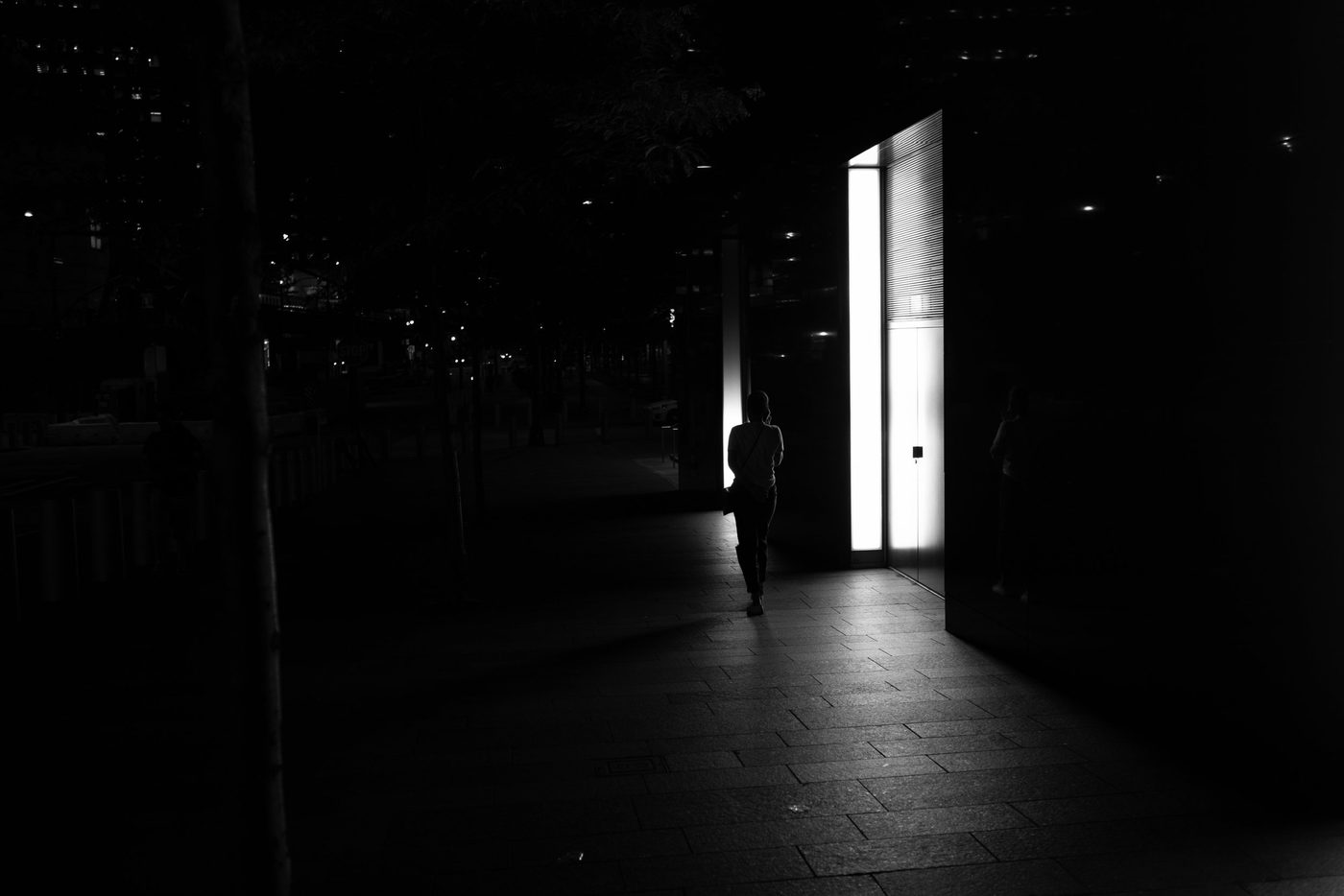 Silhouette walking toward an illuminated entrance in the darkness, New York