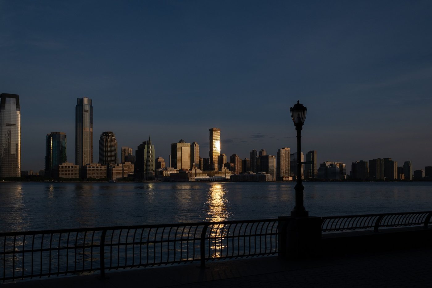 Skyline at dusk reflected on the water behind a streetlamp, New York