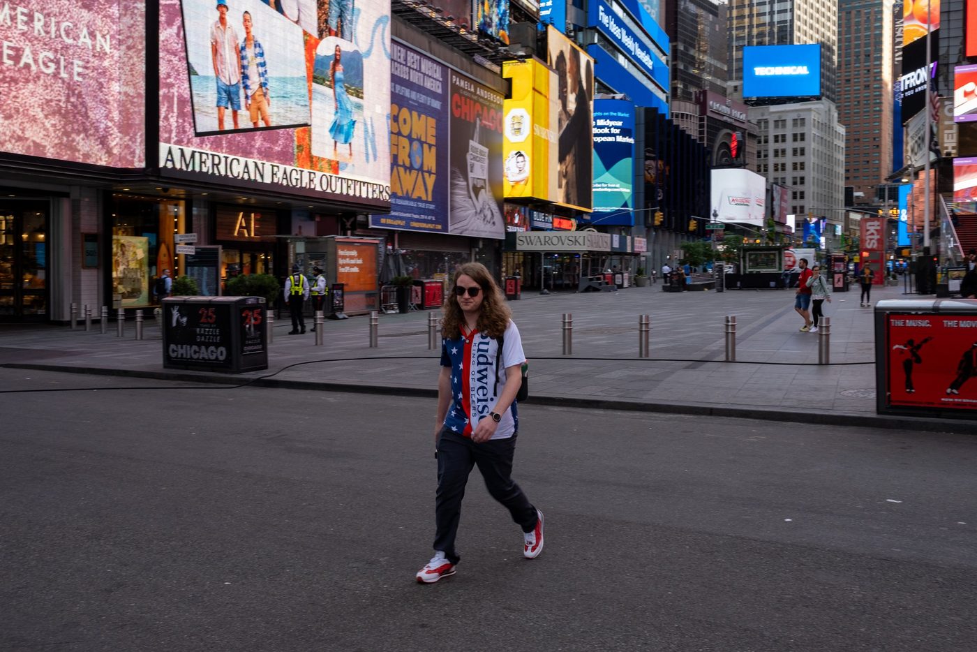 Passerby crossing an empty Times Square beneath the giant billboards, New York