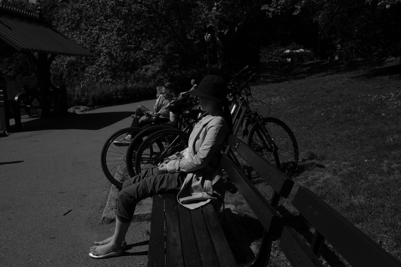 Woman sitting on a bench in the shade near parked bikes, New York