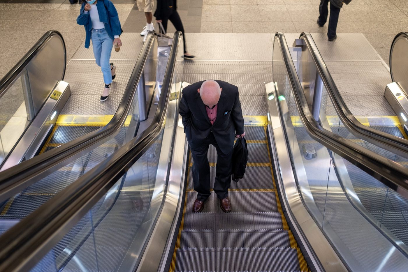 Bald man going down an escalator seen from above, New York