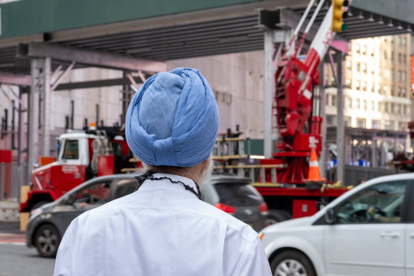 Man in a blue turban seen from behind facing a construction crane, New York