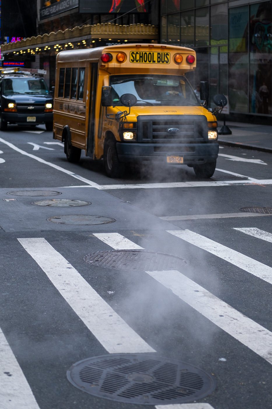 Yellow school bus crossing an intersection shrouded in steam, New York