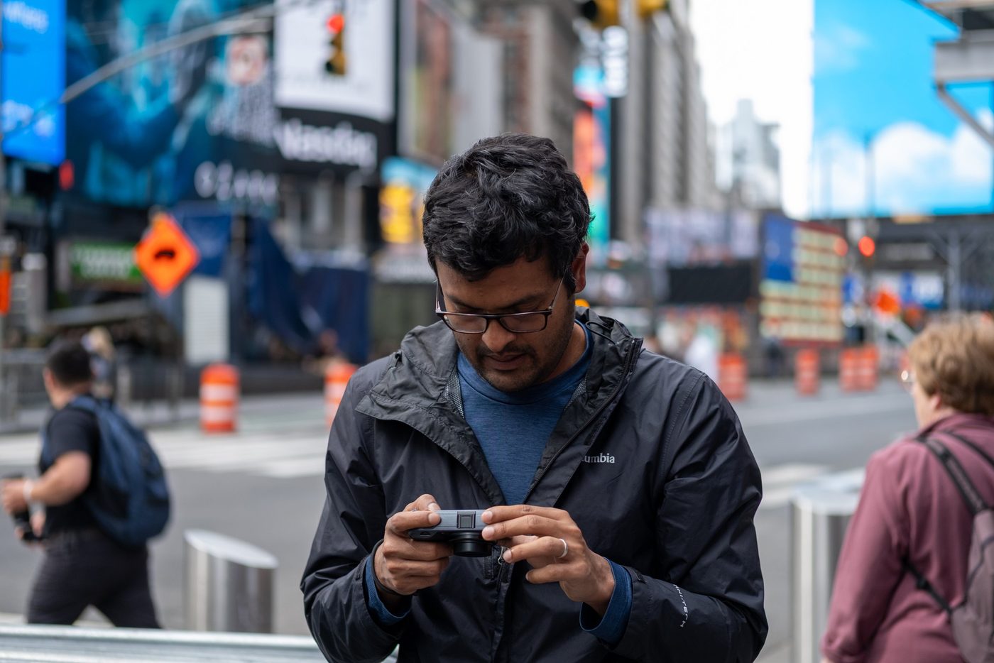 Man photographing with a compact camera amid the Times Square signs, New York