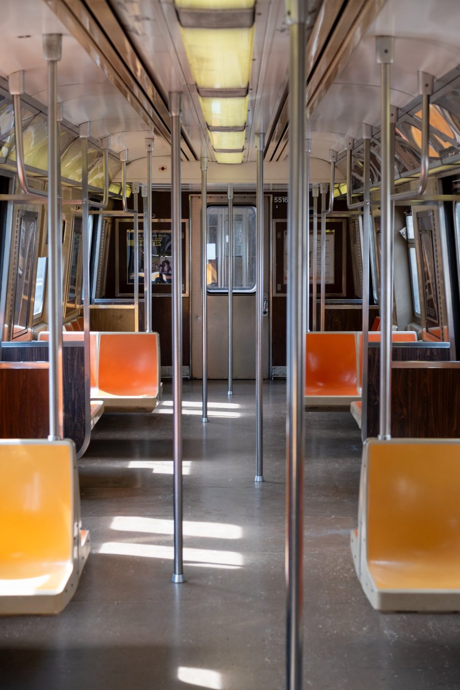 Symmetrical interior of a subway car with empty orange seats, New York