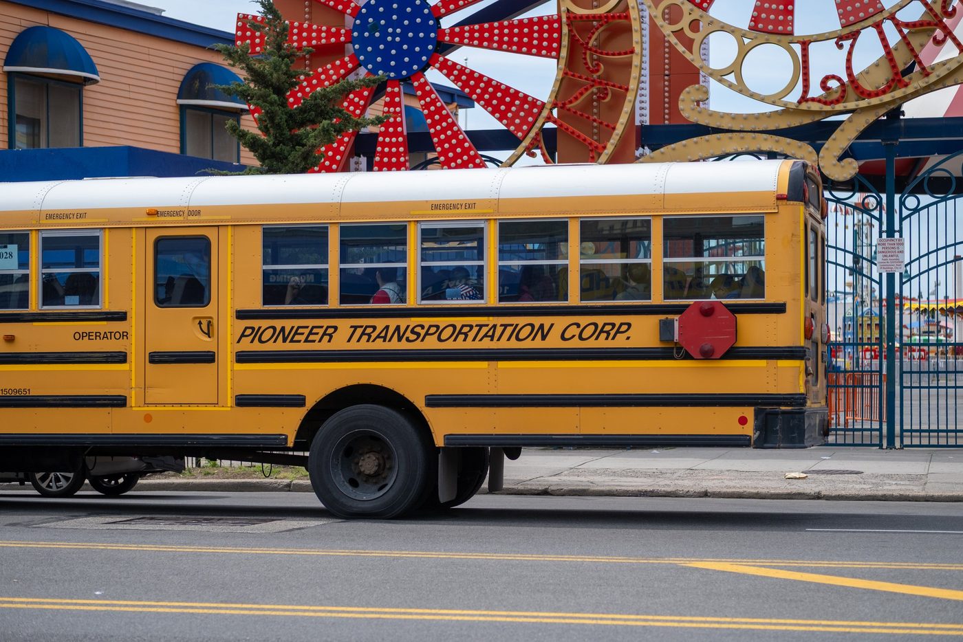 Yellow school bus parked in front of the colorful Coney Island entrance, New York