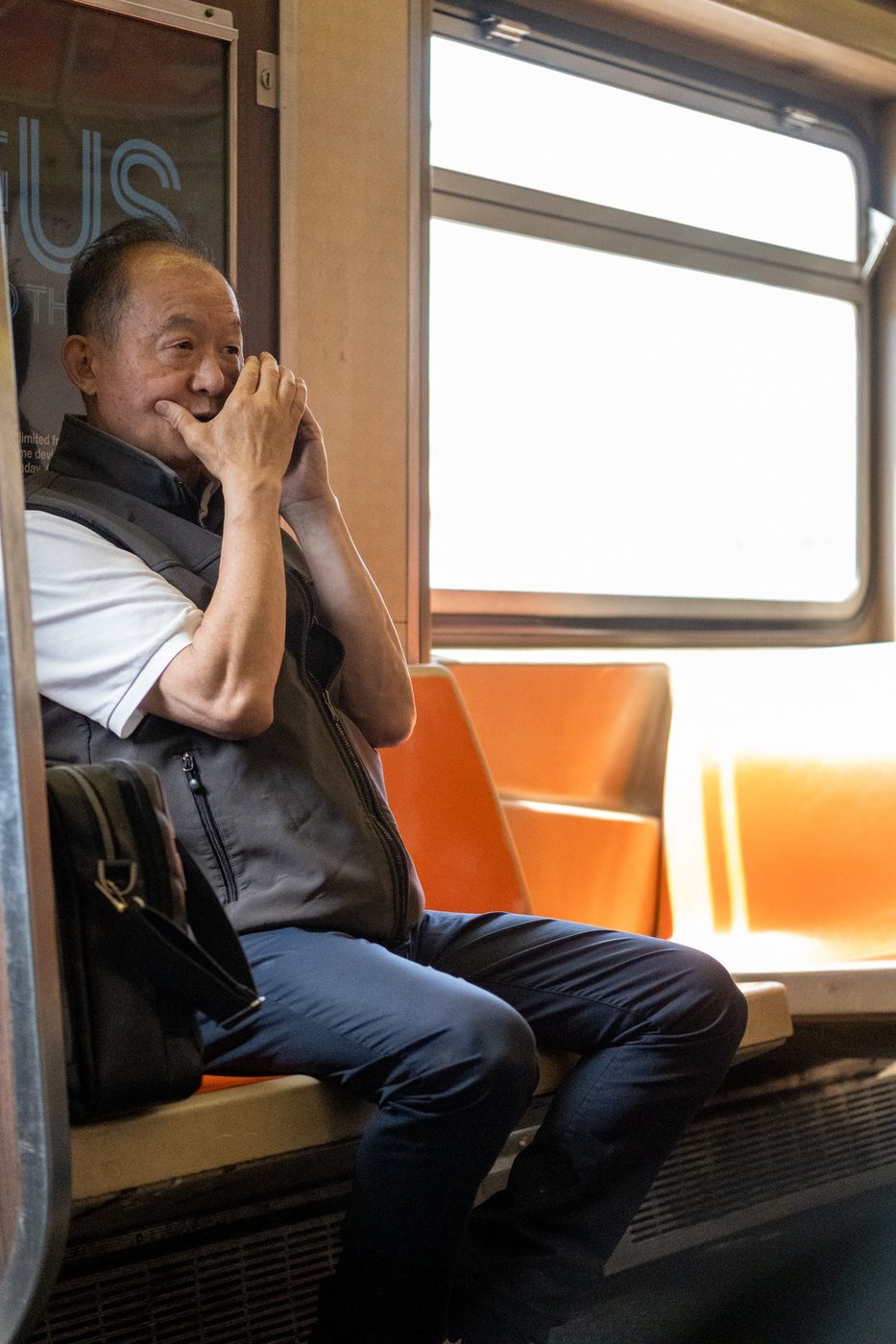 Man laughing discreetly with his hand over his mouth on the subway, New York