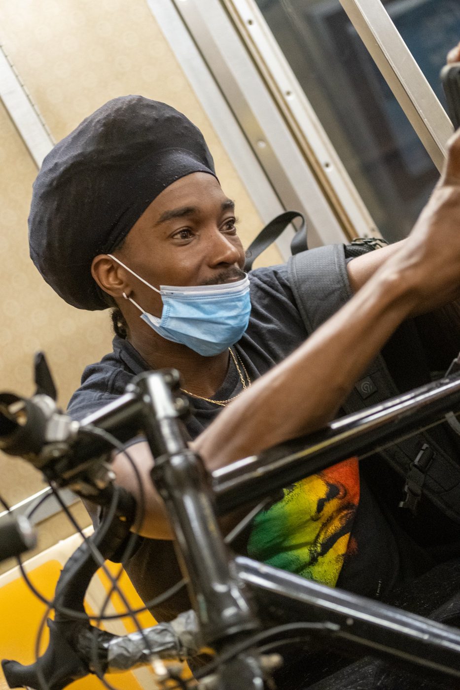 Masked cyclist holding his bike aboard the subway, New York