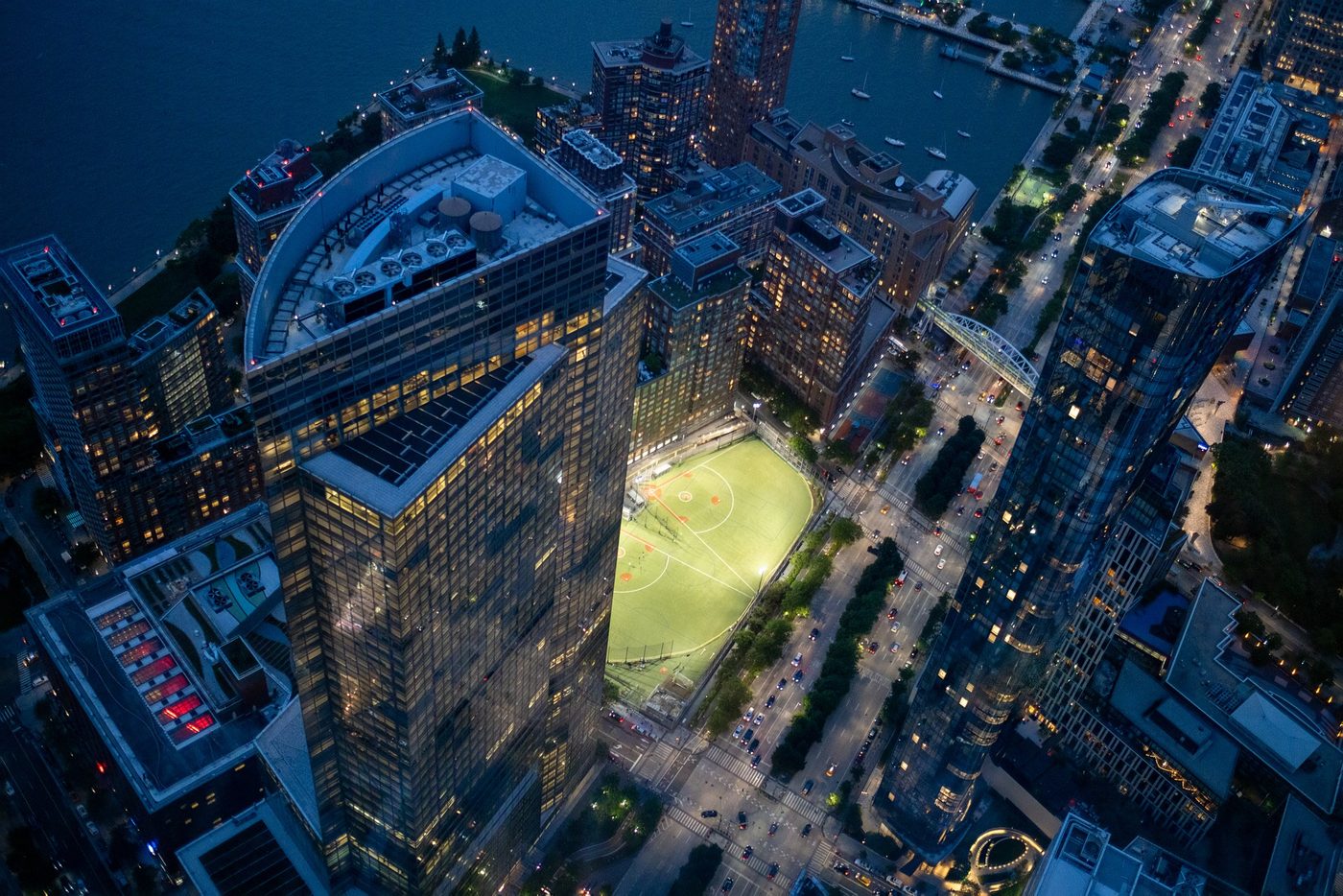 Illuminated rooftop sports field seen from above at night, New York