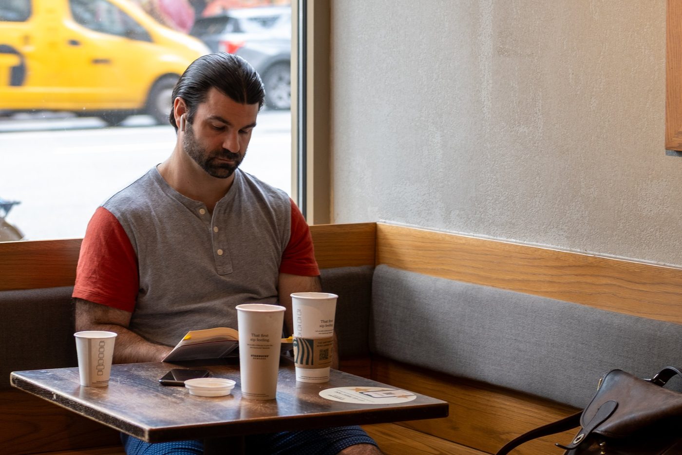 Man seated in a cafe with several cups and his book, New York