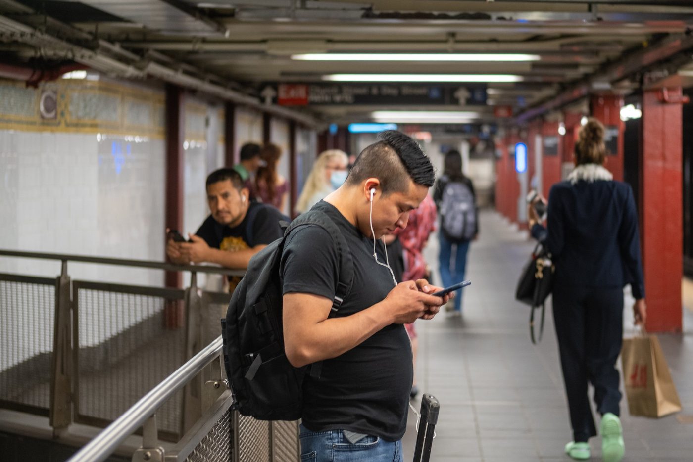 Man with a mohawk absorbed in his phone in a corridor, New York
