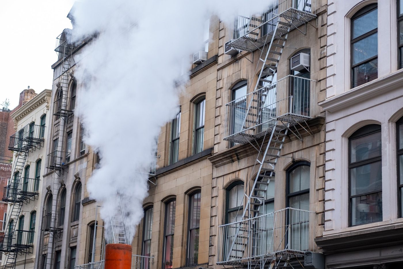 Steam rising in front of a facade with fire escapes, New York
