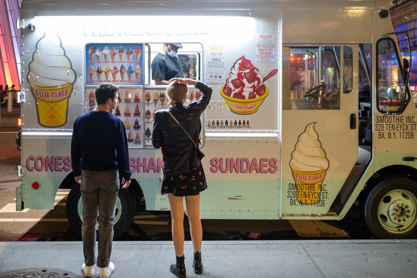 Couple ordering ice cream from a truck lit up at night, New York