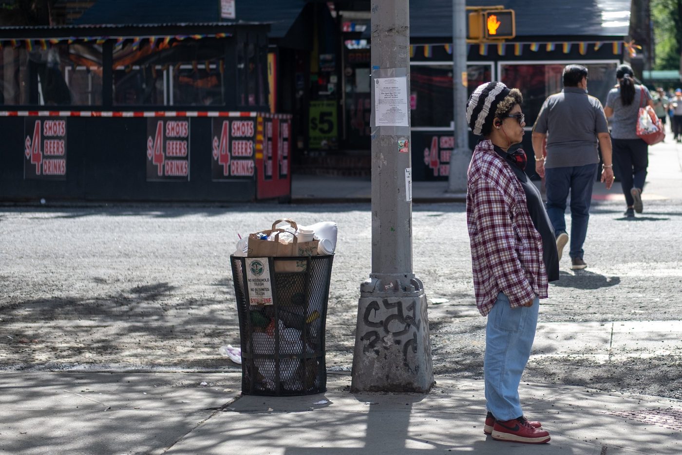 Woman in a beanie waiting near an overflowing trash can, New York