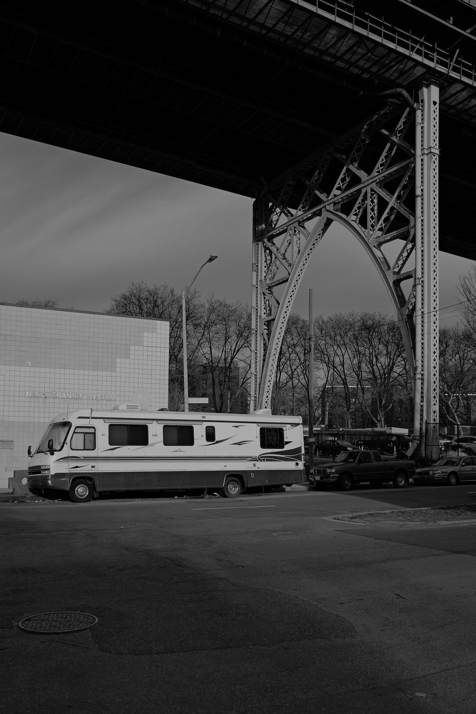 Camper van parked beneath the metal arch of a railway bridge, New York