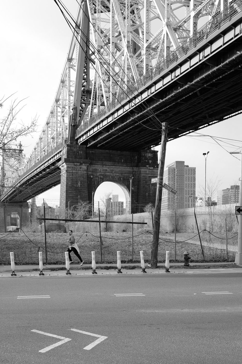 Runner passing beneath the massive beams of a bridge, New York