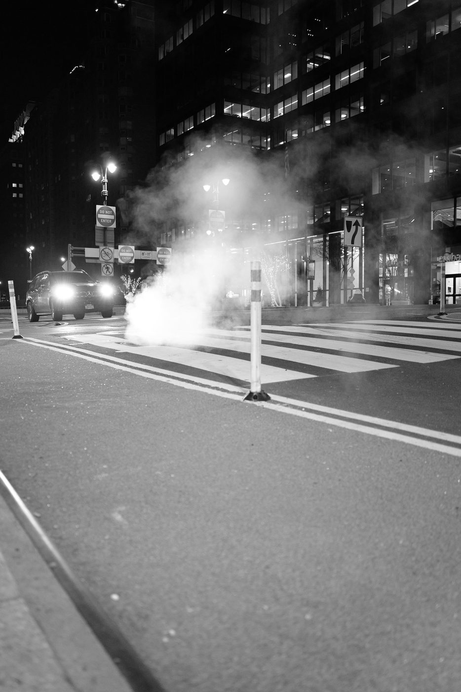 Cloud of steam in front of a car with its headlights on at night, New York