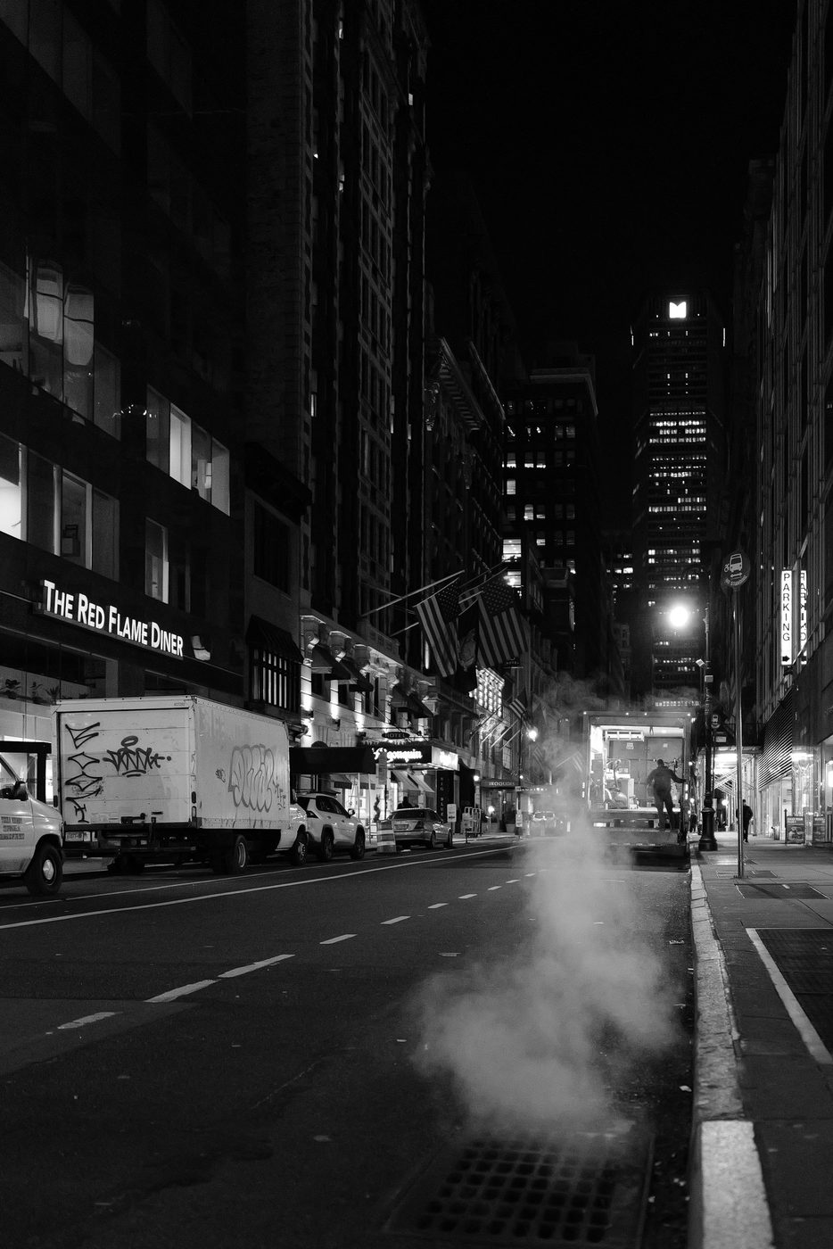 Silhouette walking down a nighttime street lined with American flags, New York