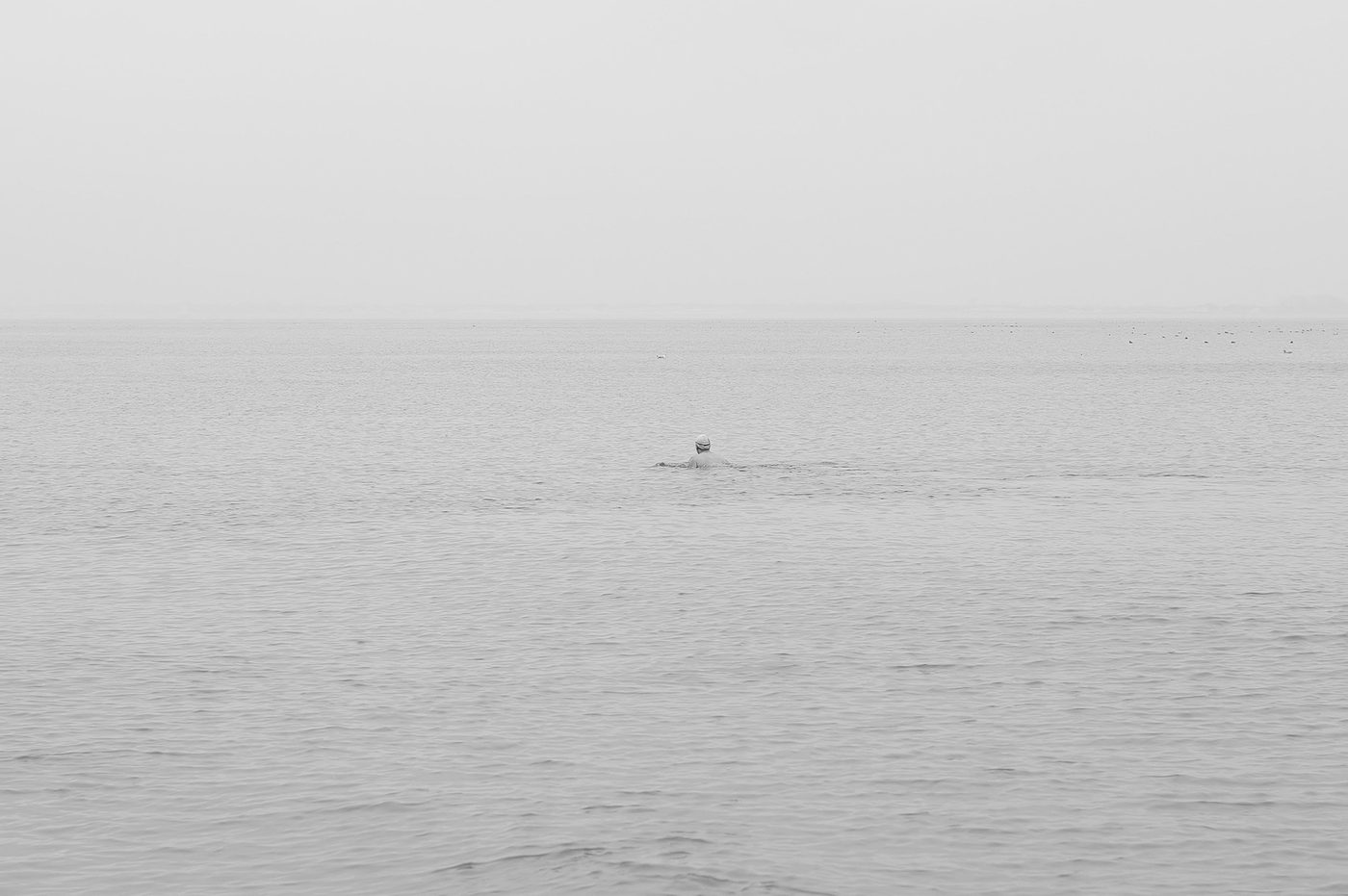 Lone swimmer in the distance in a misty sea, New York