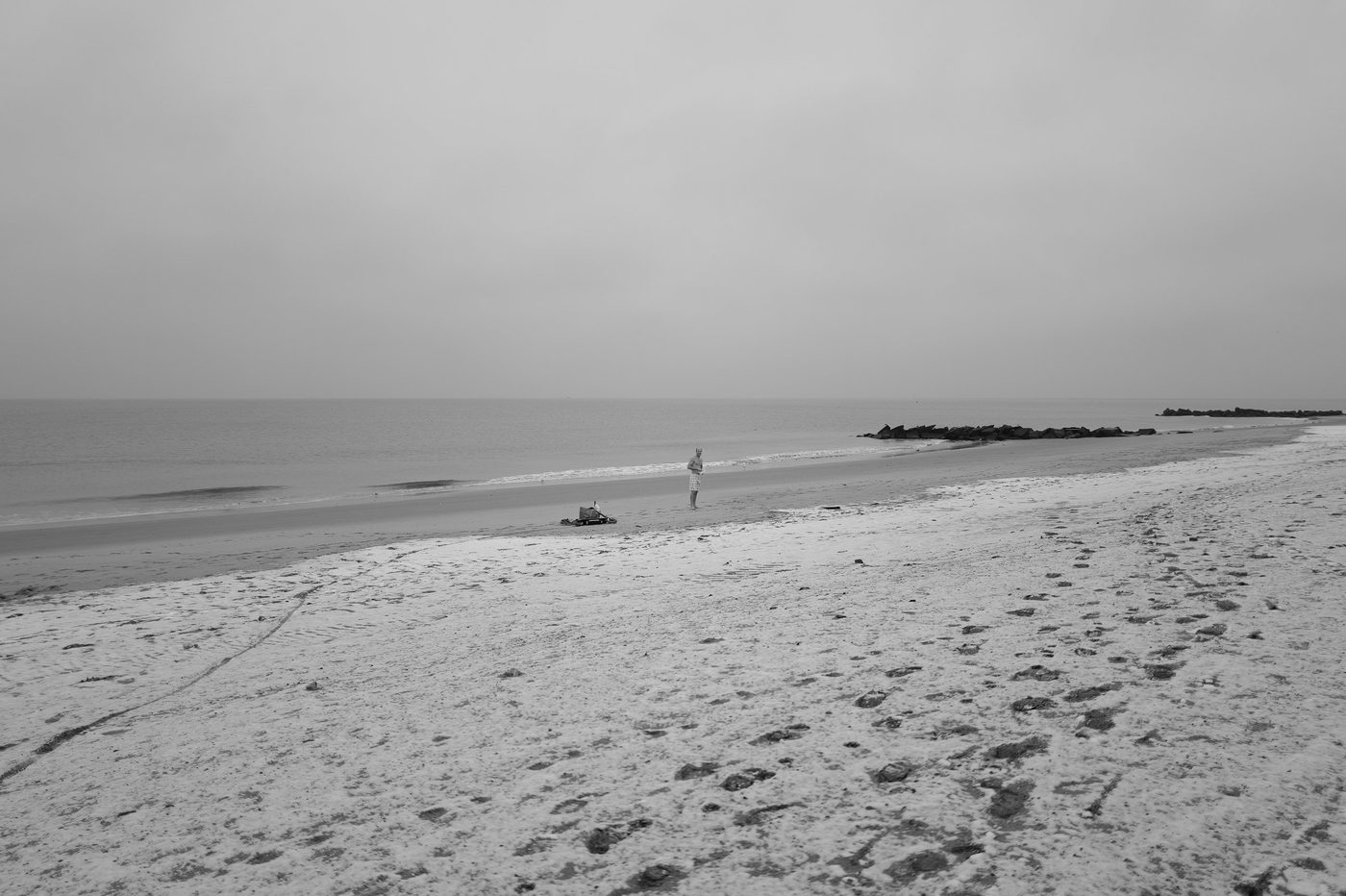Man standing alone near his belongings on a deserted beach, New York