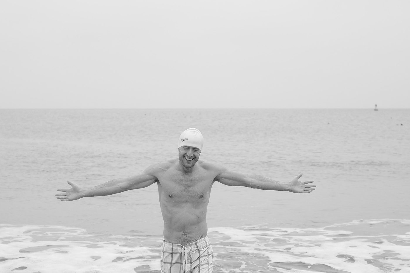 Smiling swimmer with arms spread in the waves, New York