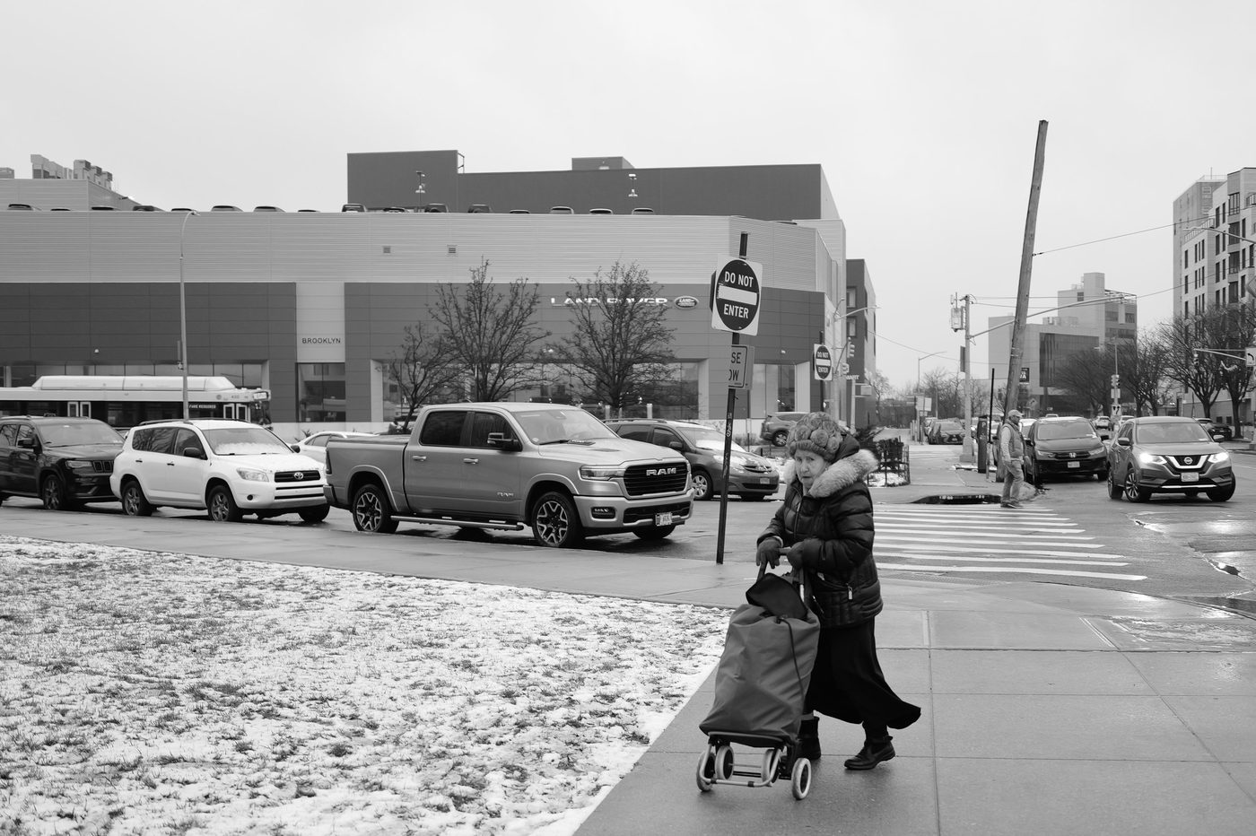 Elderly woman pulling a shopping cart crossing the snowy street, New York