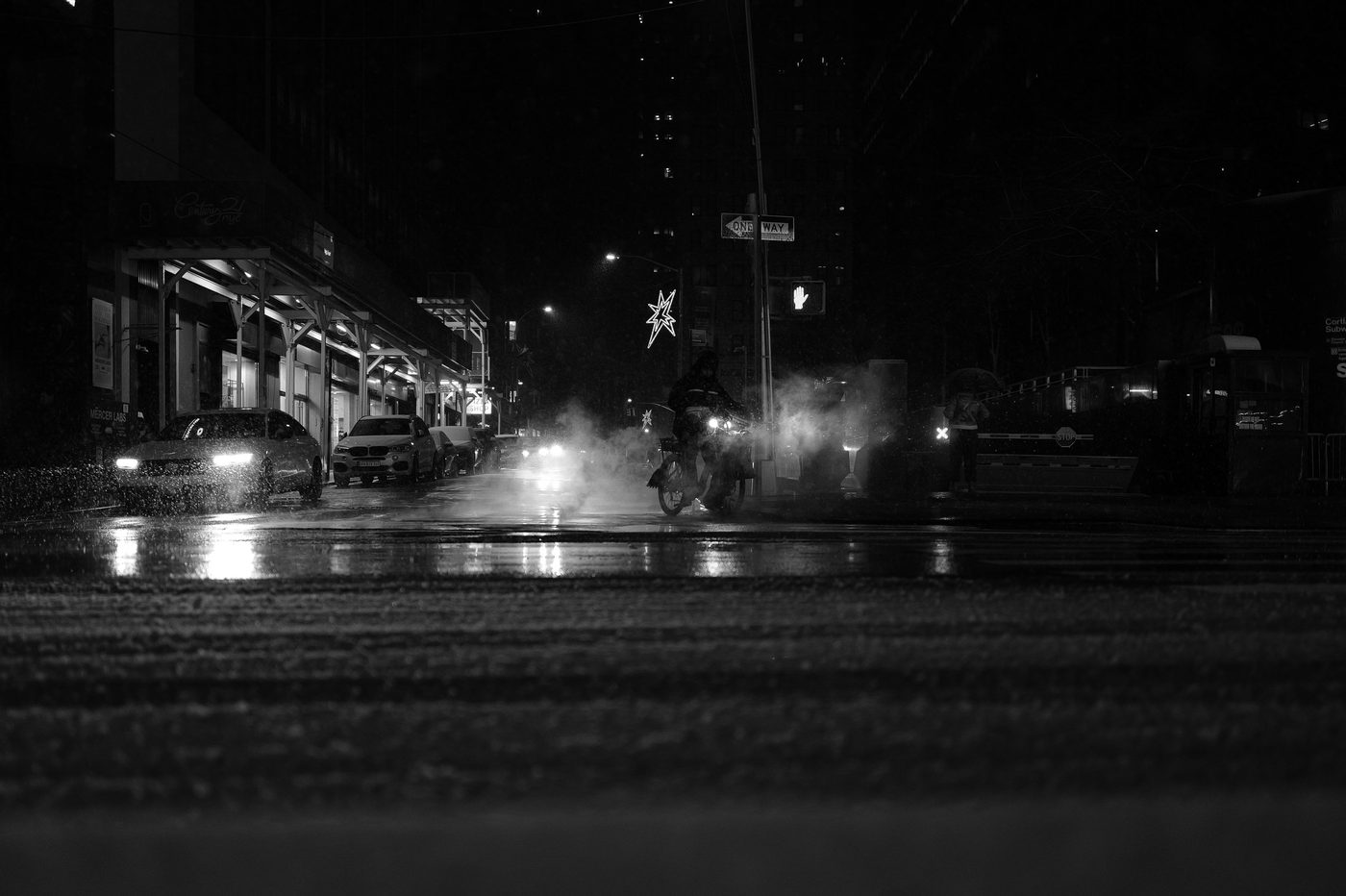 Cyclist crossing a rainy, misty street at night, New York