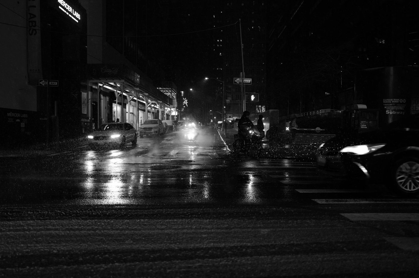 Cars and cyclists on a snowy street at night, New York