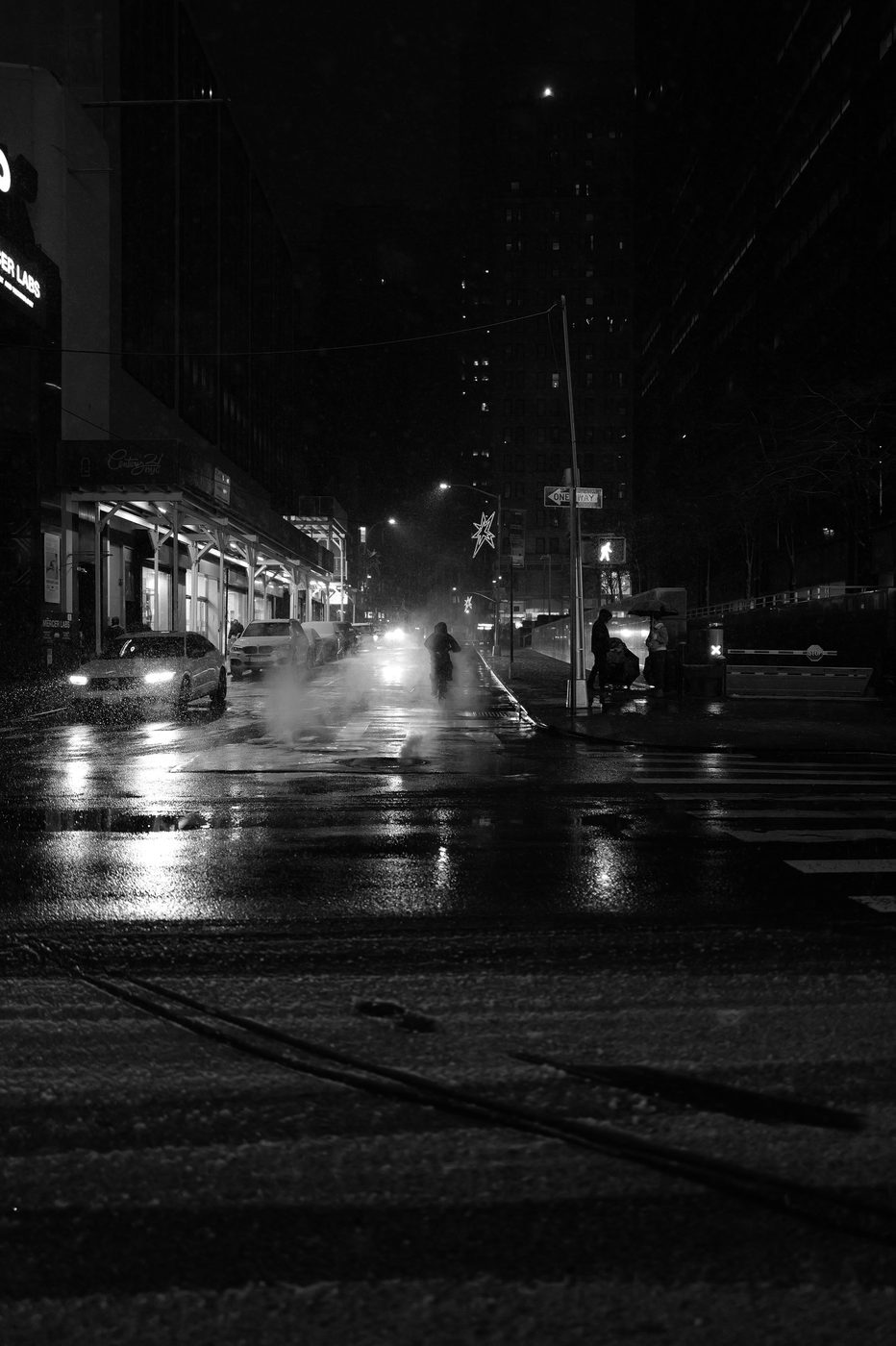 Cyclist riding through the snow past passersby under umbrellas, New York
