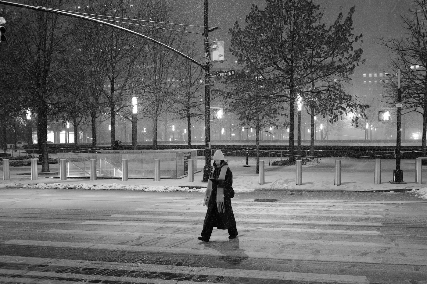Woman in a beanie crossing the snowy street near the Greenwich Street sign, New York