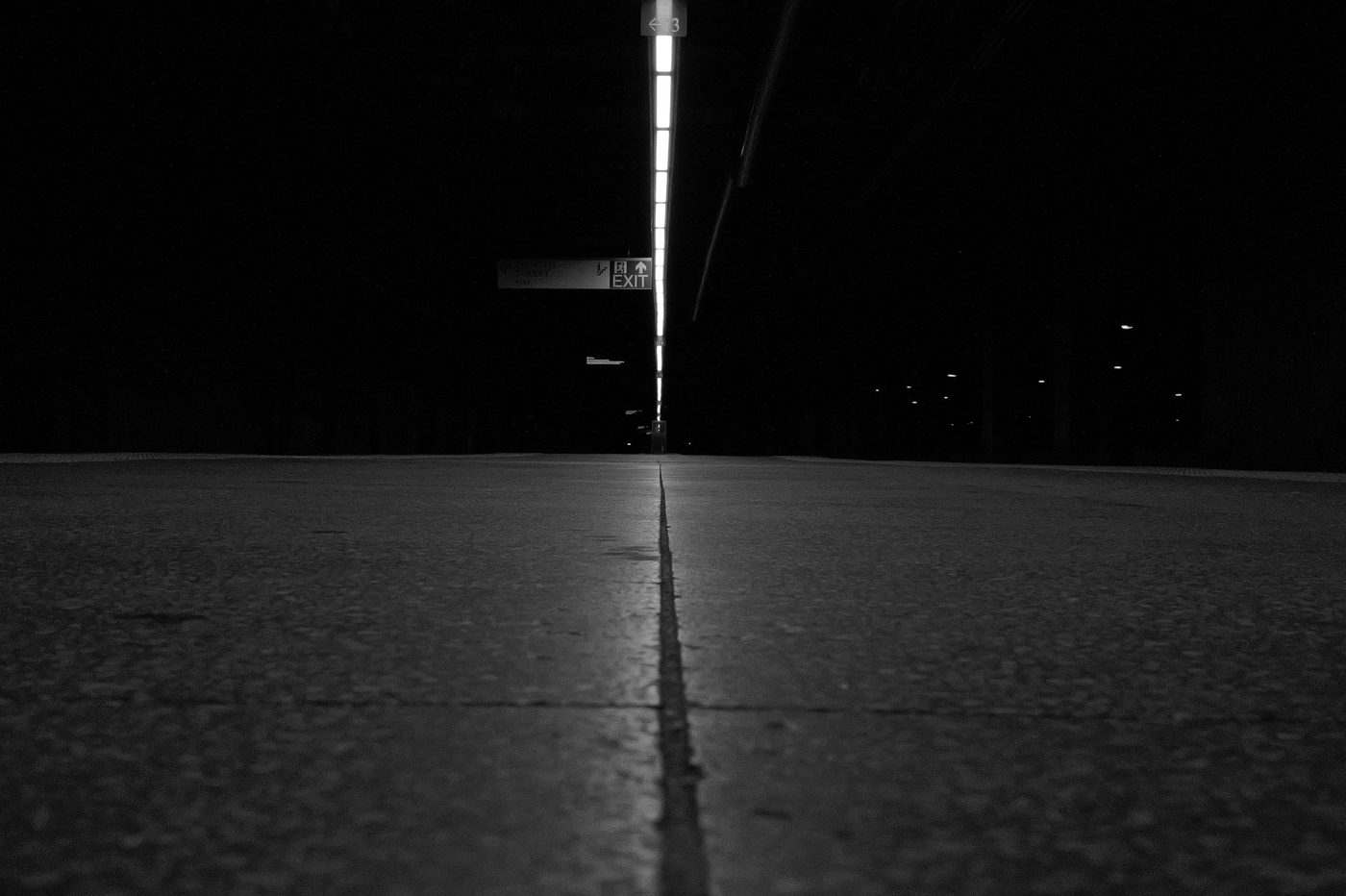 Dark subway corridor leading toward a lit Exit sign, New York