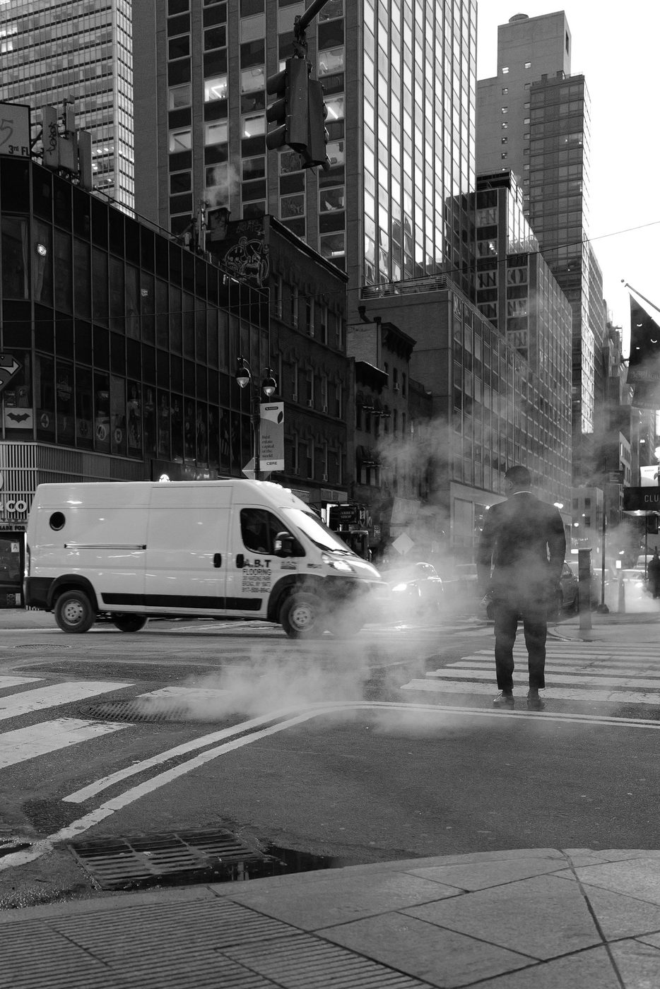 Man waiting at the crosswalk in the steam, skyscrapers in the background, New York