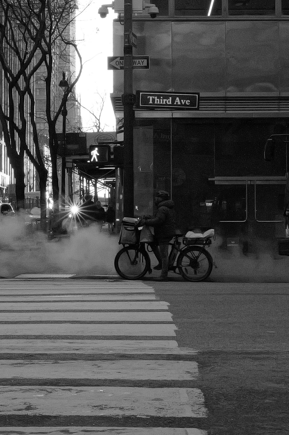 Delivery cyclist stopped at the corner of Third Avenue in the steam, New York