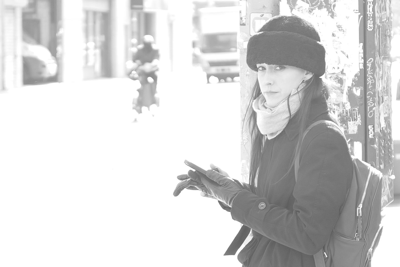 Woman in a fur hat looking at the camera, phone in hand, New York