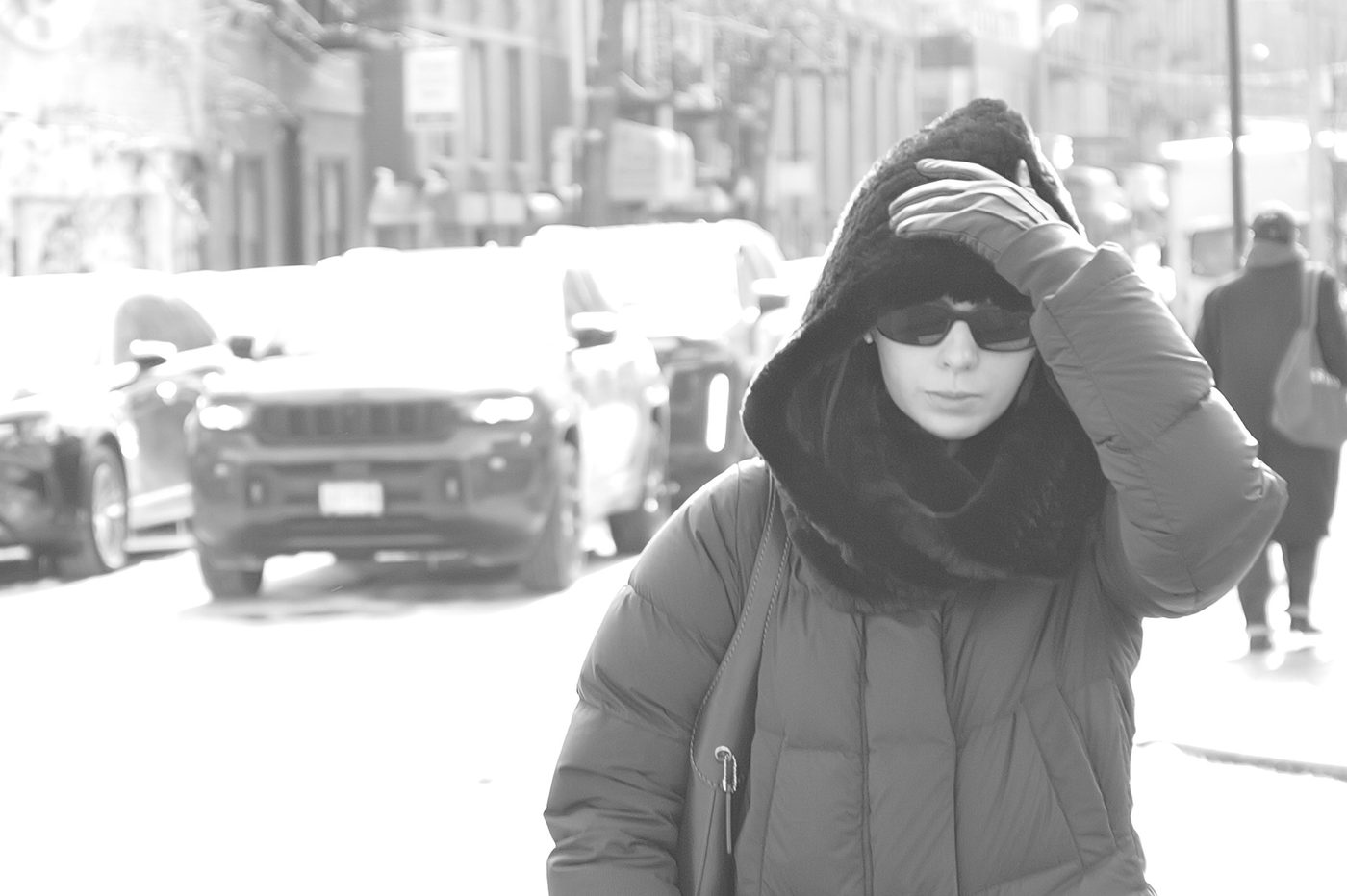 Woman adjusting her fur-trimmed hood, sunglasses on, New York