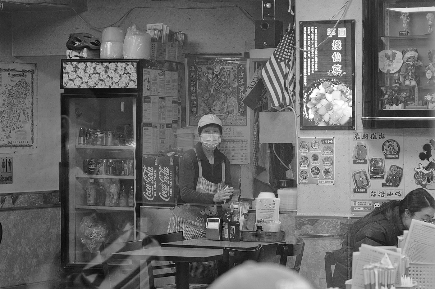 Masked employee behind the counter of a Taiwanese restaurant, New York