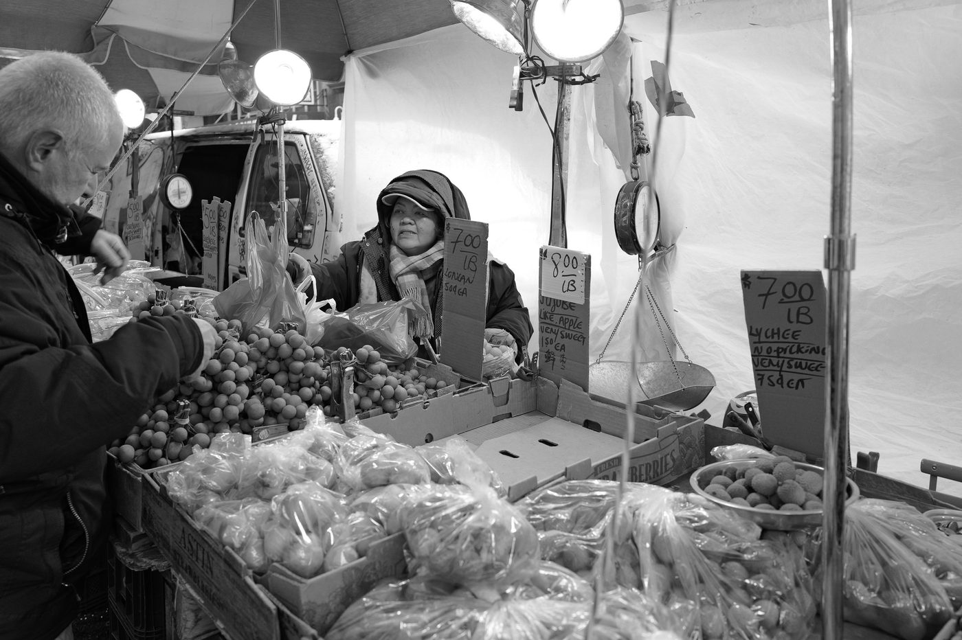 Fruit vendor selling lychees and longans at a market, New York