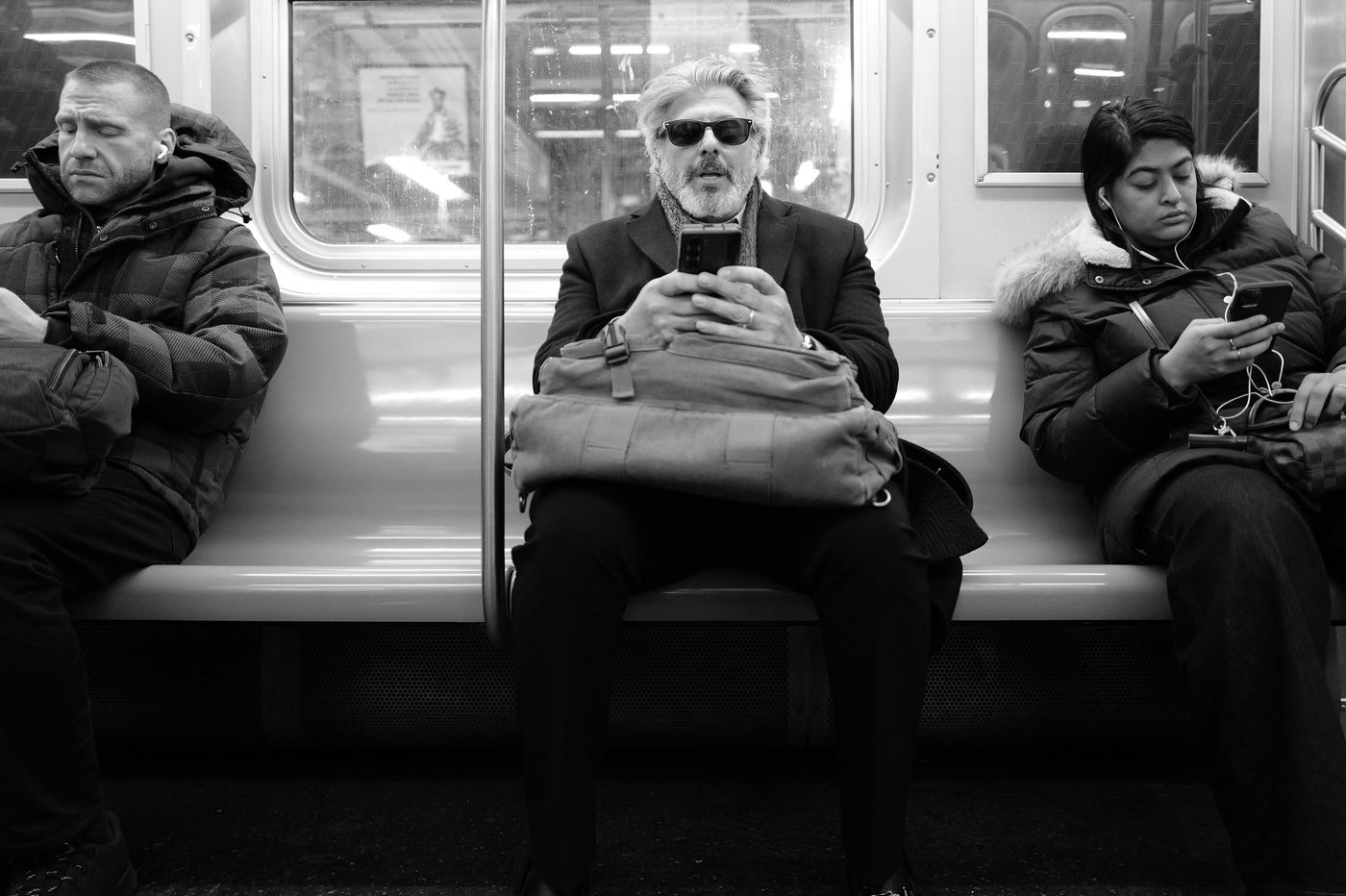 Three subway passengers each absorbed in their phone, New York