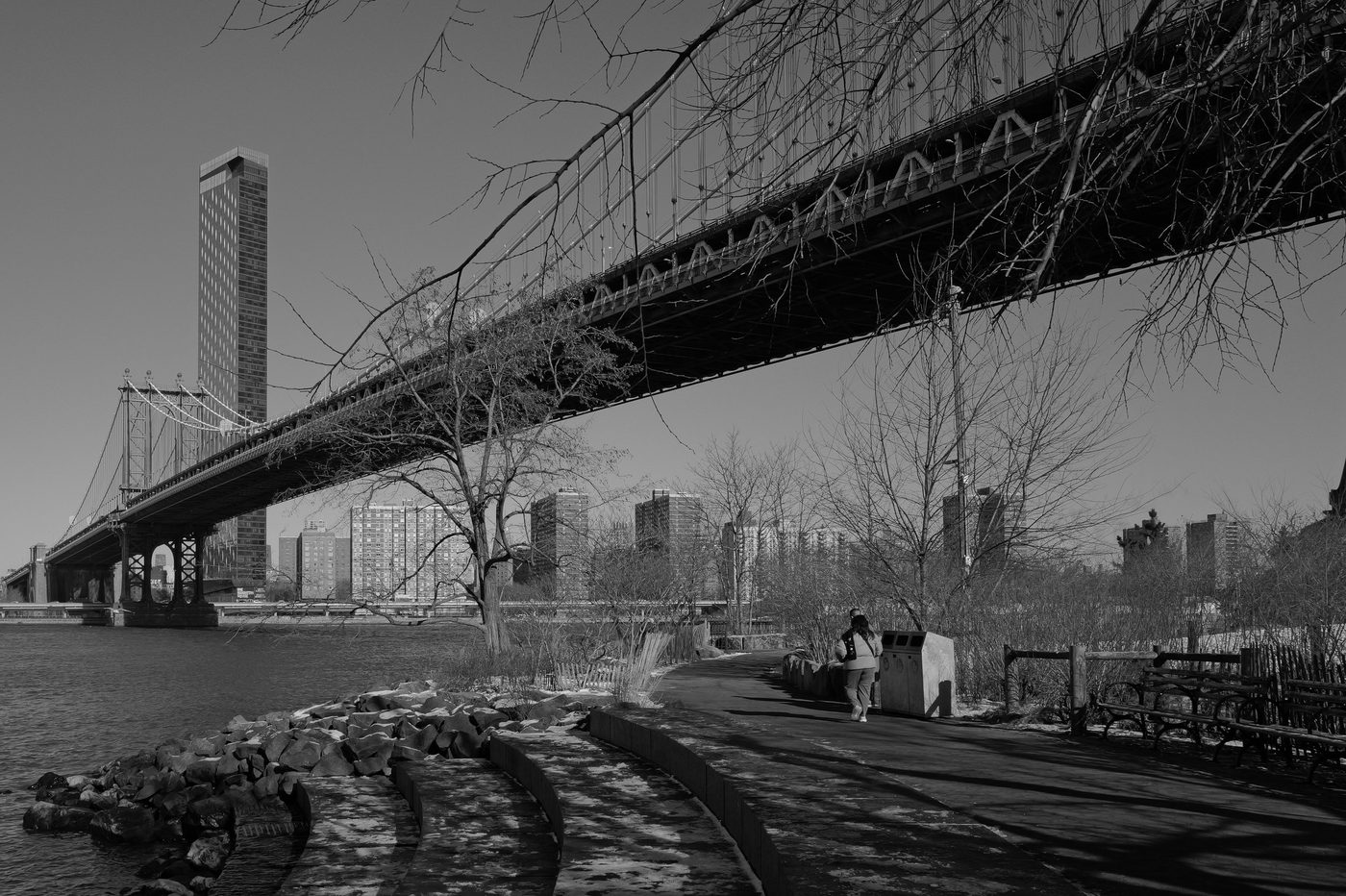 Female runner passing beneath the Manhattan Bridge by the water, New York