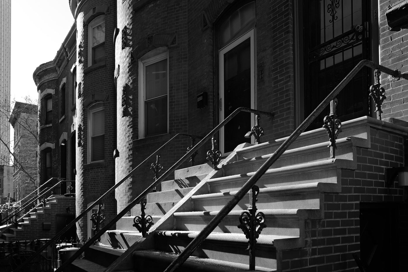 Ornate stone stoop of a brownstone facade, strong shadows, New York