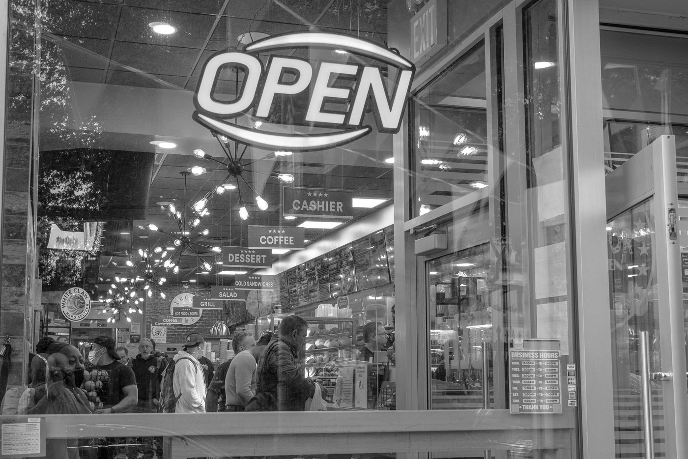 Open sign reflected on the window of a crowded deli, New York