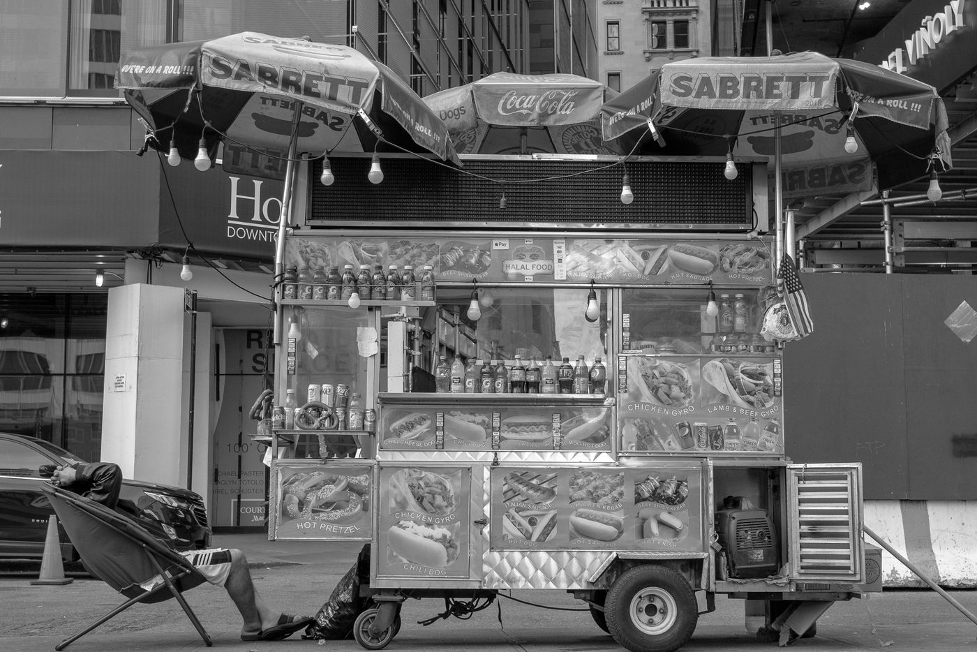 Hot dog vendor resting near his Sabrett cart, New York