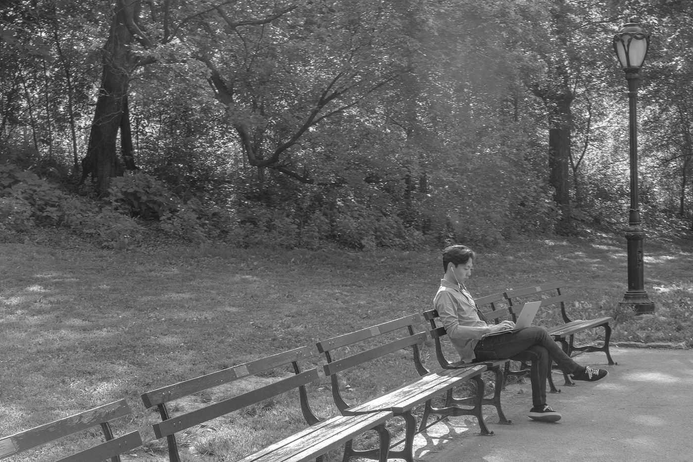 Man working on his laptop alone on a bench, New York