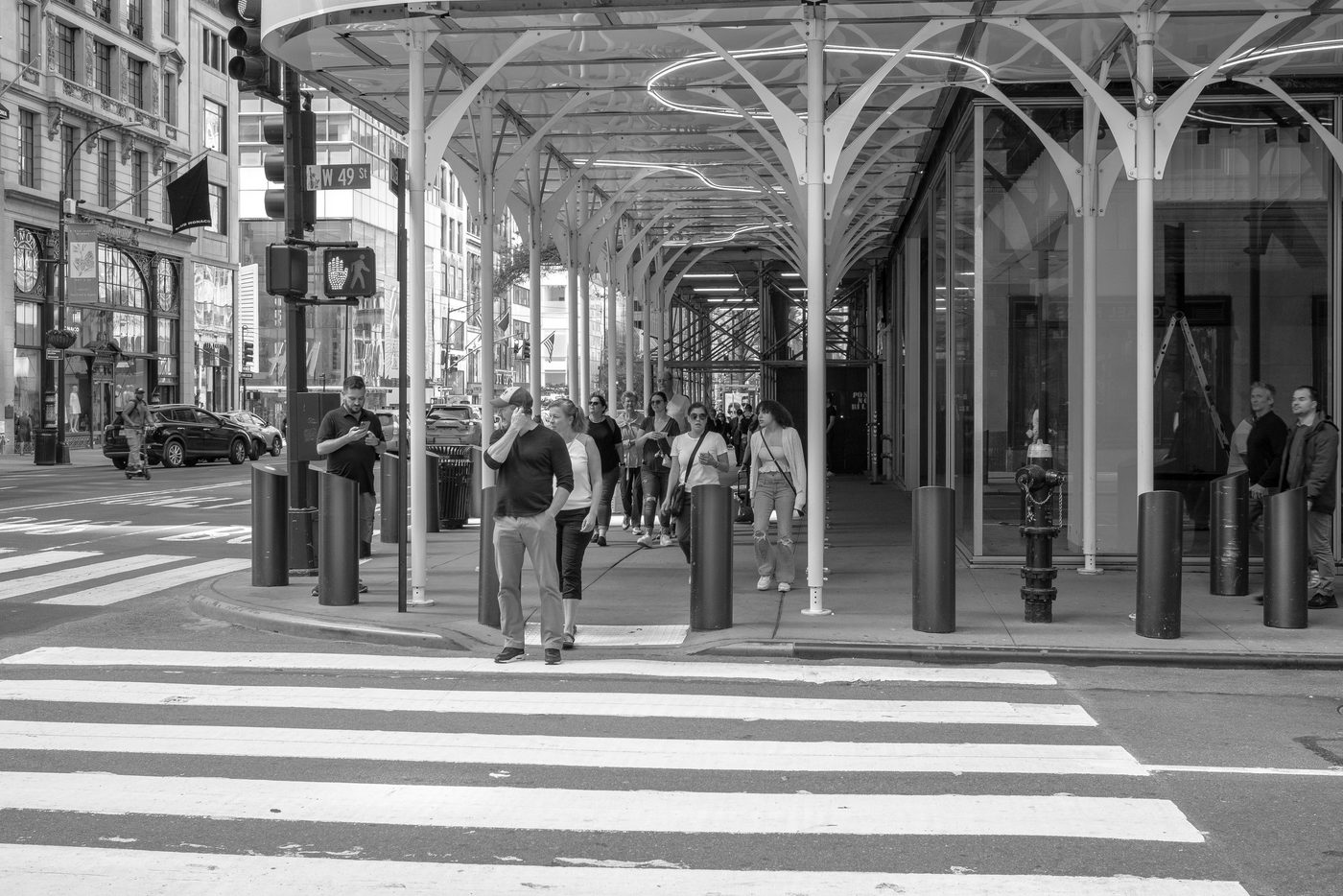Passersby beneath a metal arch structure on 49th Street, New York