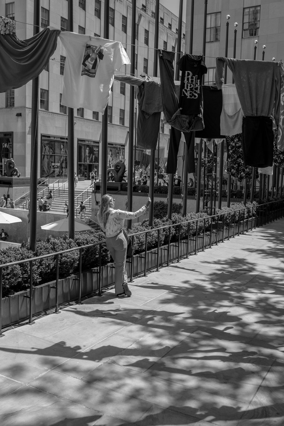 Woman photographing an installation of hanging t-shirts, New York