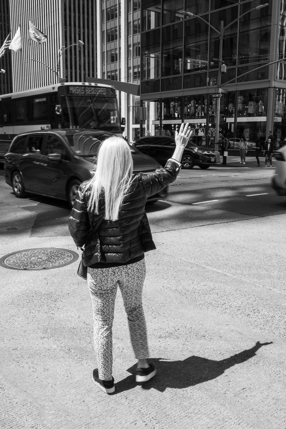 Woman hailing a taxi with a raised arm amid traffic, New York
