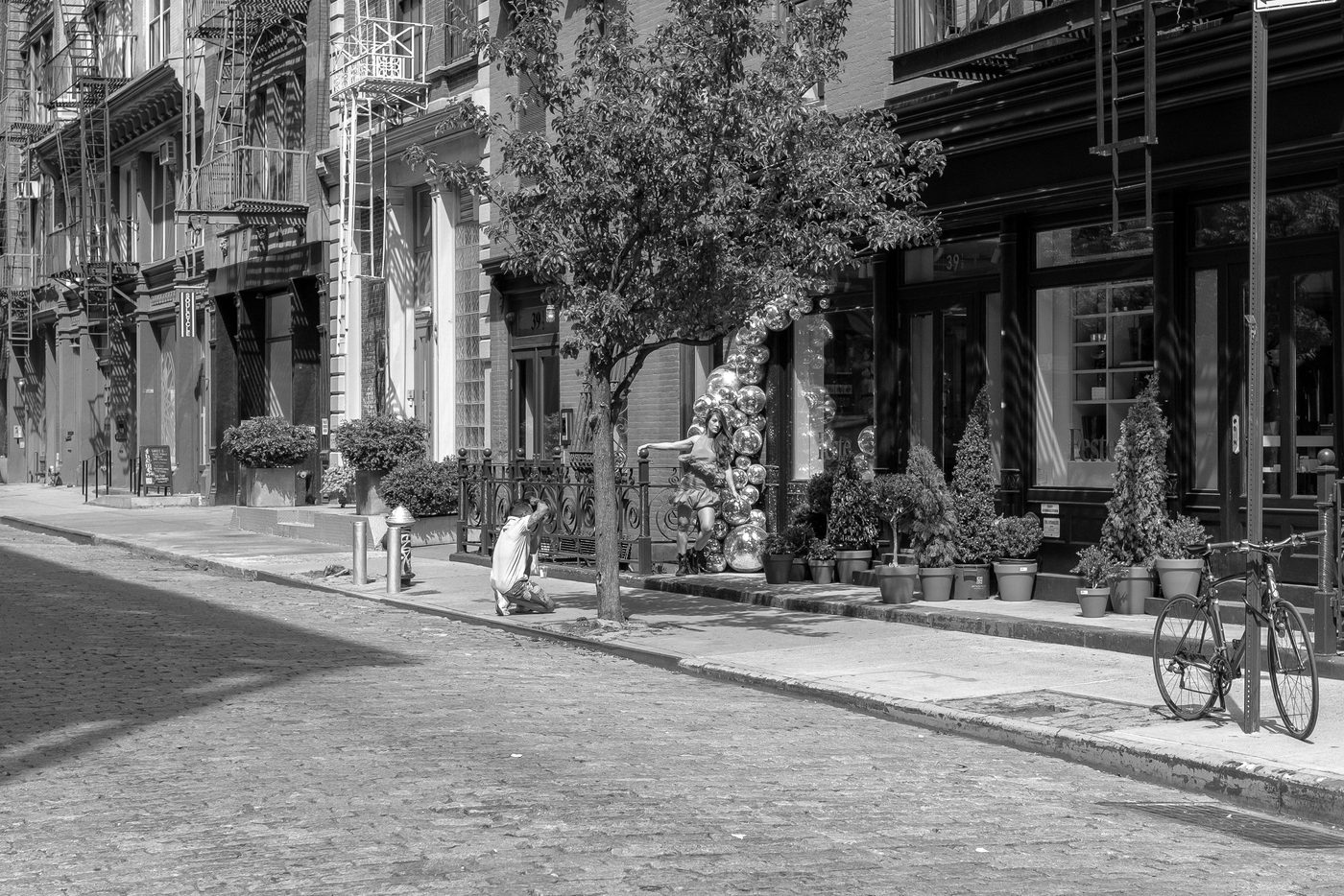 Photographer kneeling and shooting a model in front of a silver balloon sculpture, New York