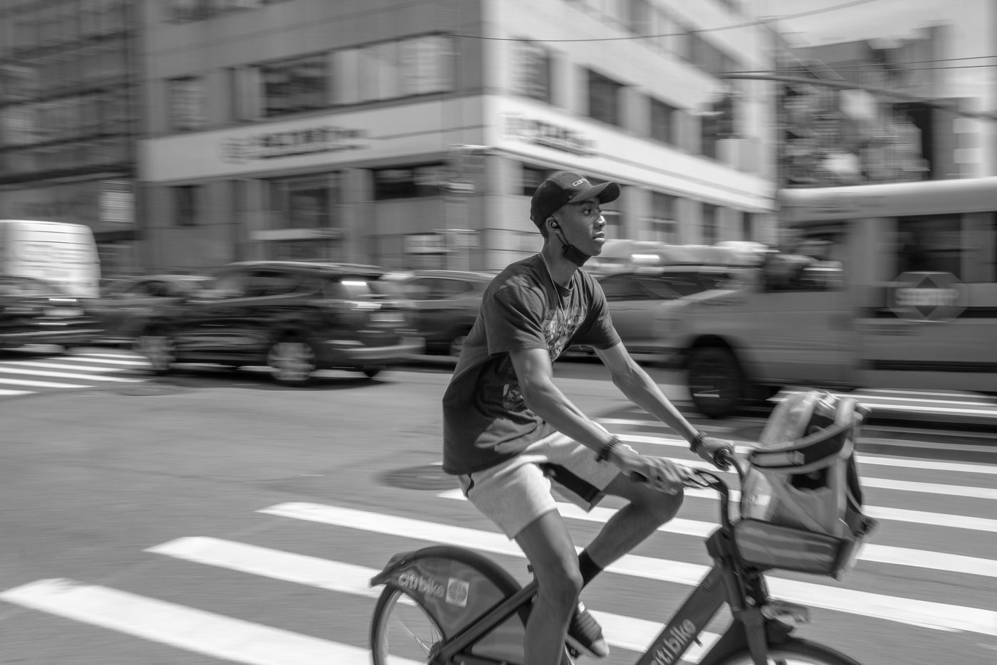 Blurred cyclist in a cap crossing an intersection at high speed, New York