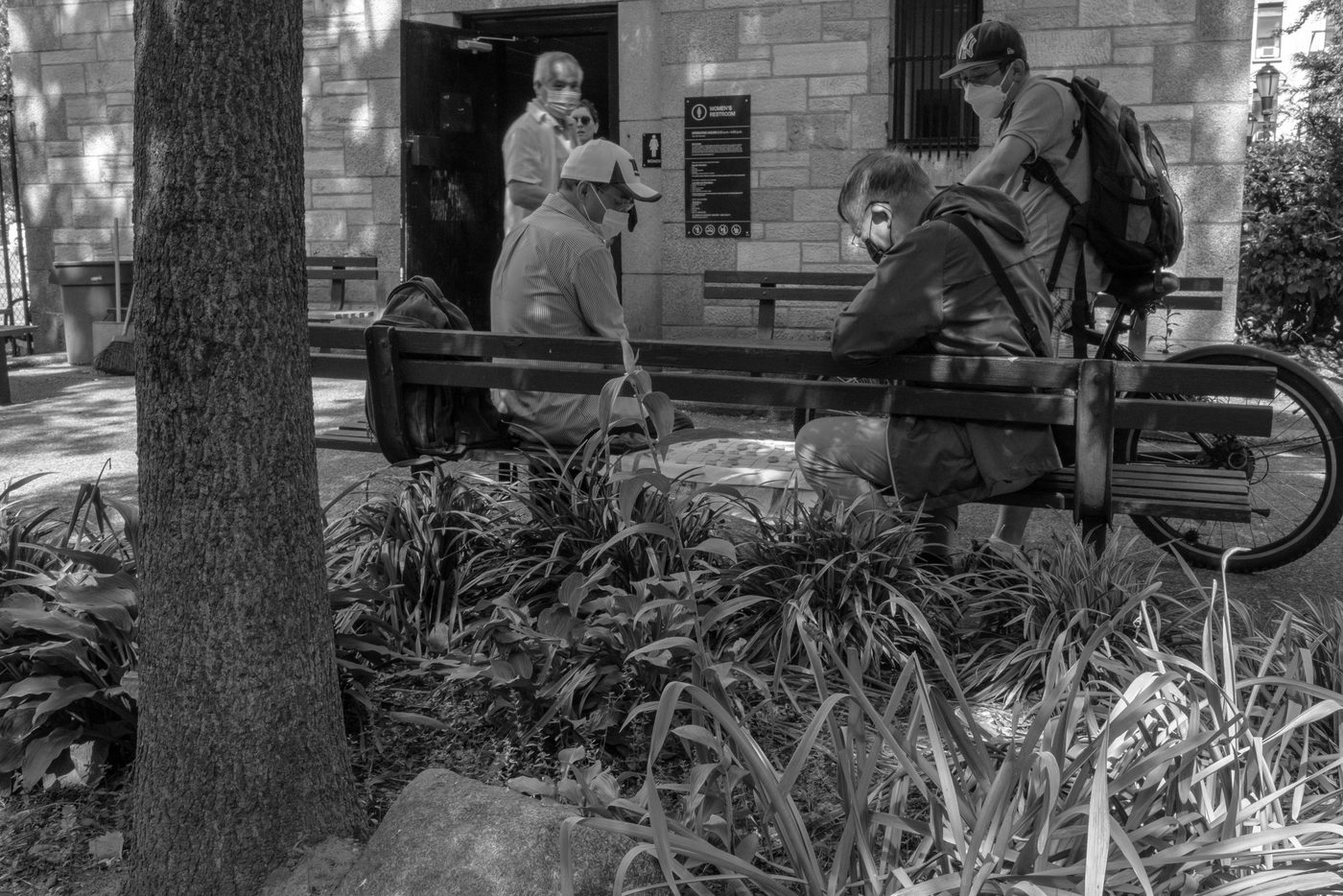 Three masked men playing checkers on a park bench, New York